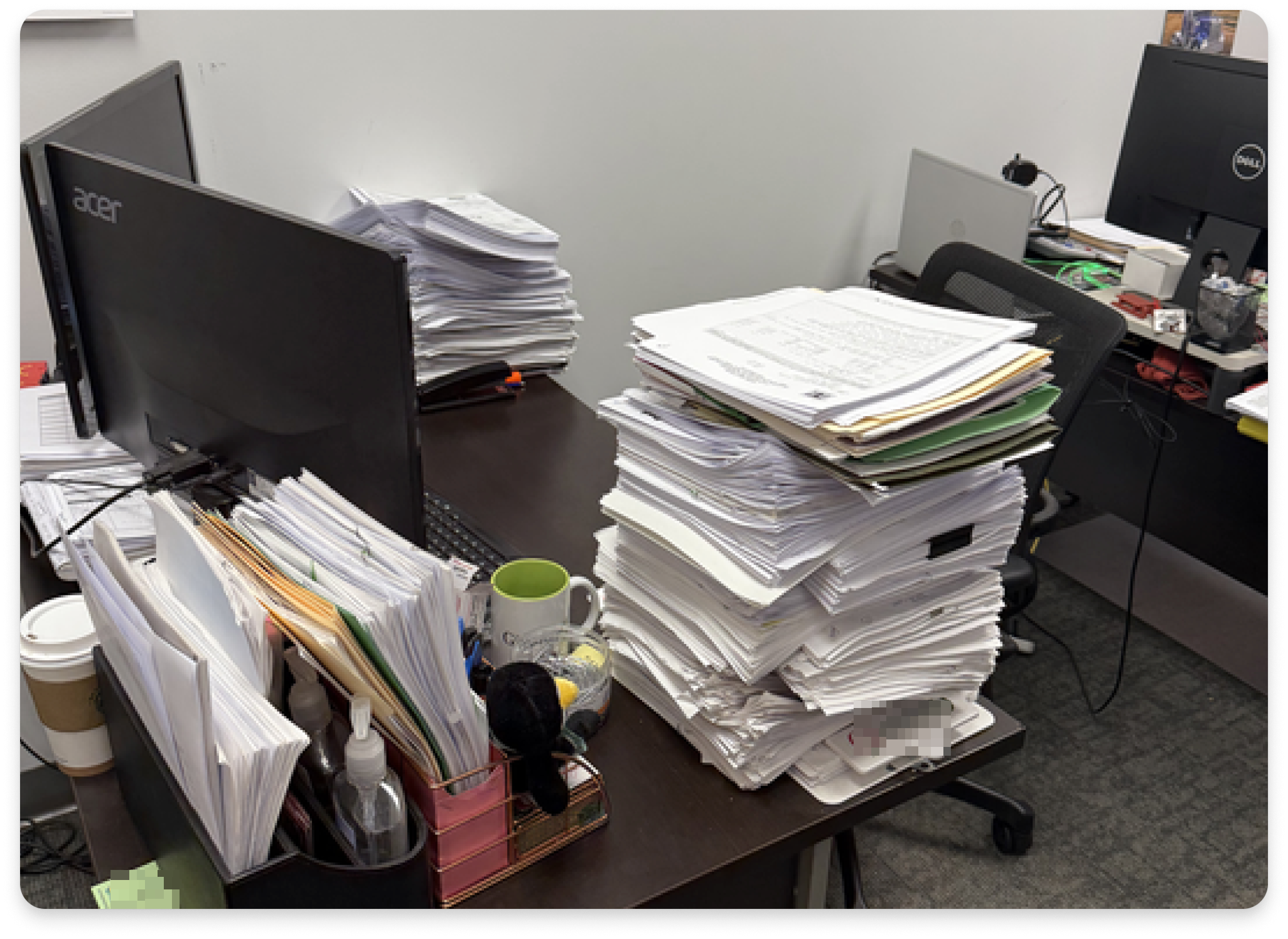 A real customer's desk overflowing with stacks of paper invoices and folders, illustrating the manual backlog problem Smart Upload was built to solve.
